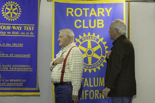 A couple of men standing in front of a banner

Description automatically generated