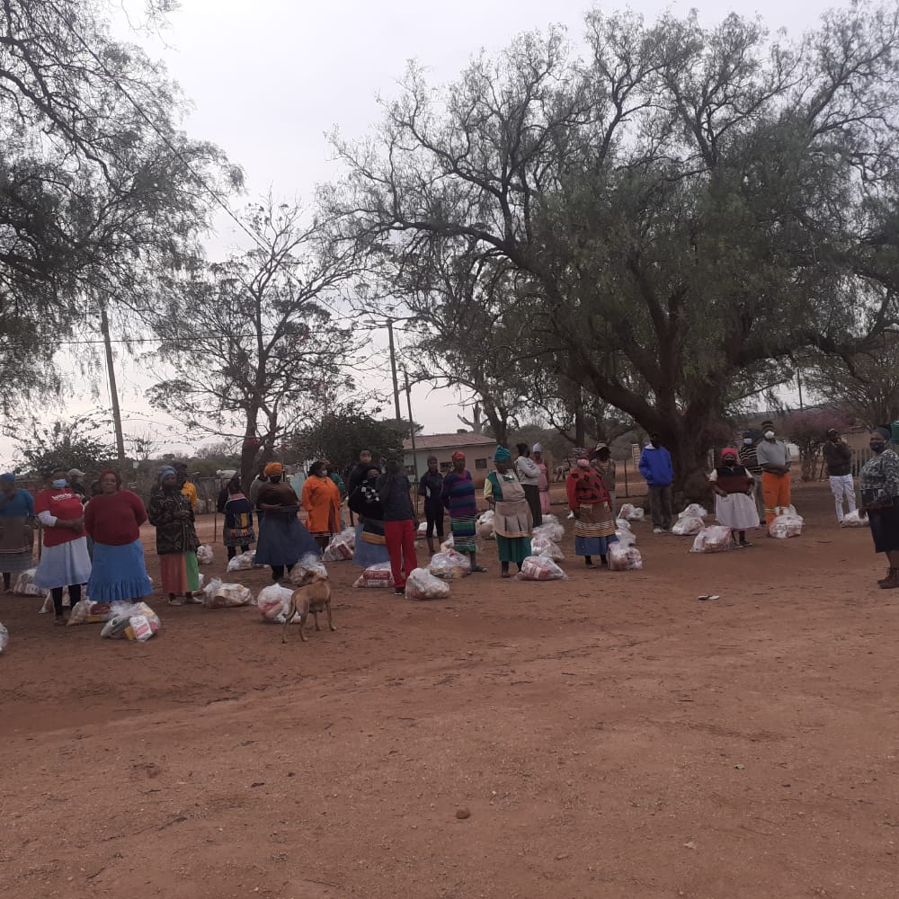 A group of people standing in a dirt area

Description automatically generated