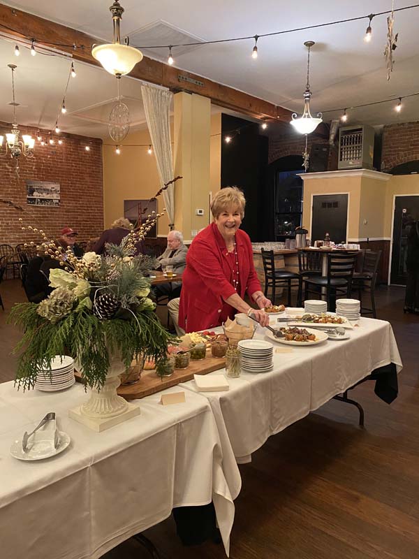 A person in a red shirt standing at a table with food

Description automatically generated