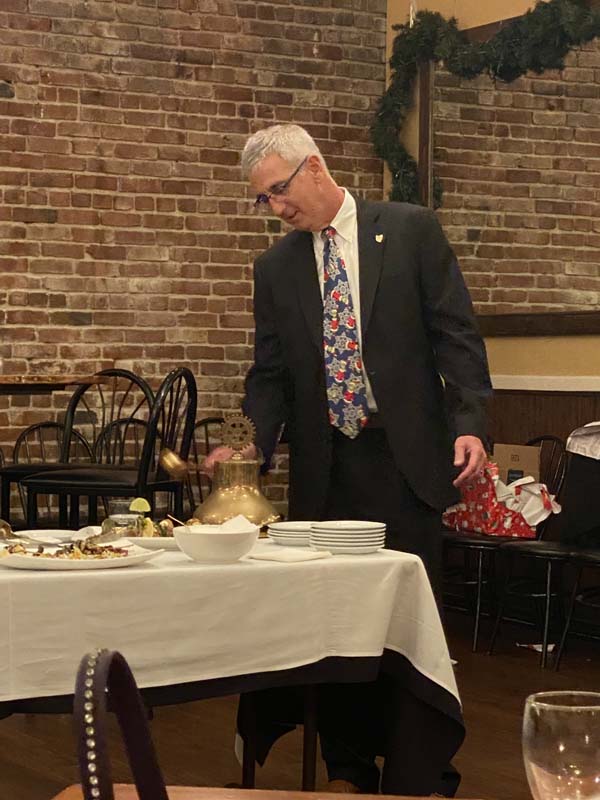 A person in a suit pouring food into a table

Description automatically generated