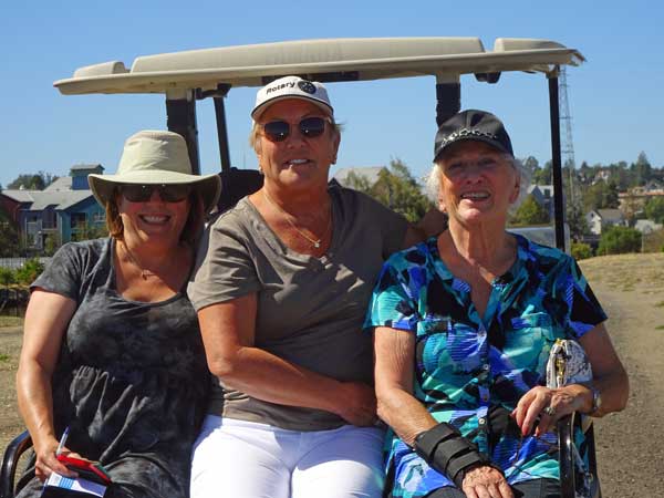 A group of women sitting in a golf cart

Description automatically generated