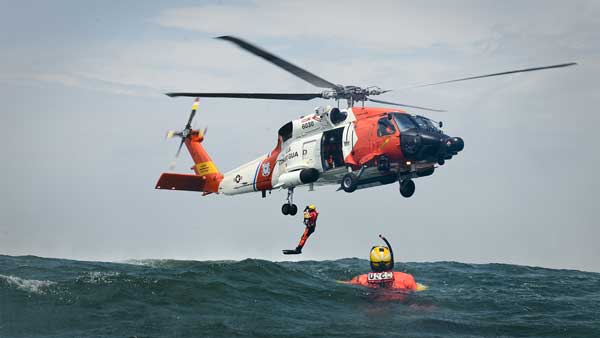 A helicopter with a person in the water

Description automatically generated