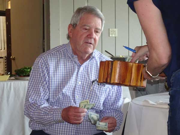 A person holding a wooden bowl with money

Description automatically generated