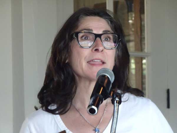 A person with glasses speaking into a microphone

Description automatically generated