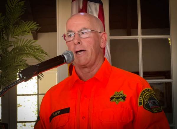 A person in an orange uniform speaking into a microphone

Description automatically generated