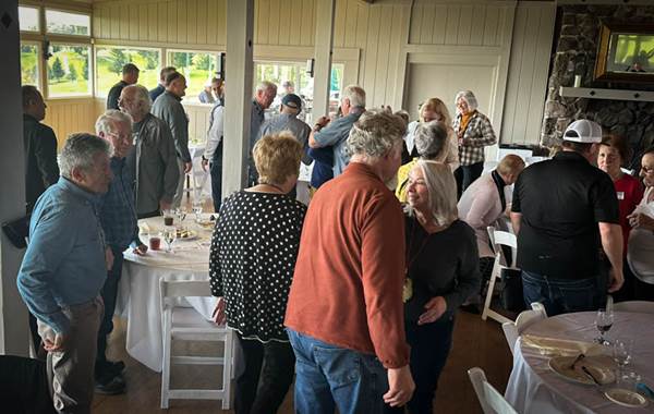 A group of people standing around tables

Description automatically generated