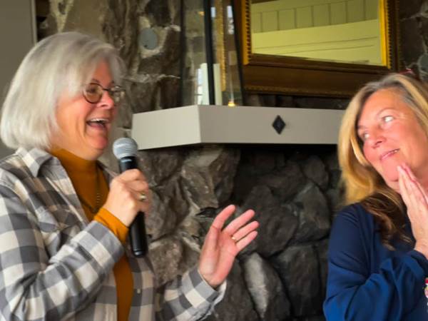 Two women holding a microphone and smiling

Description automatically generated